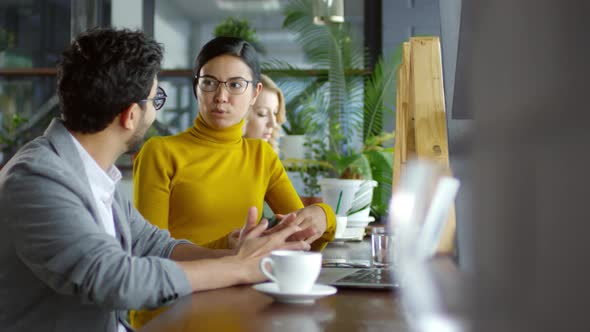 Asian Businesswoman Speaking with Male Coworker in Cafe