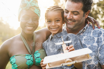 Multiracial family having fun outdoor in city park playing with wood toy - Focus on father face / Photodune, Misc