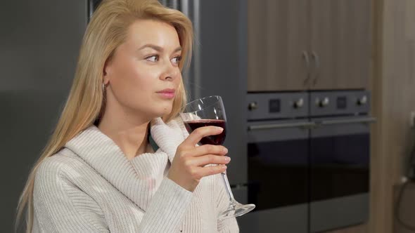 Gorgeous Woman Enjoying Drinking Red Wine at Home at the Kitchen