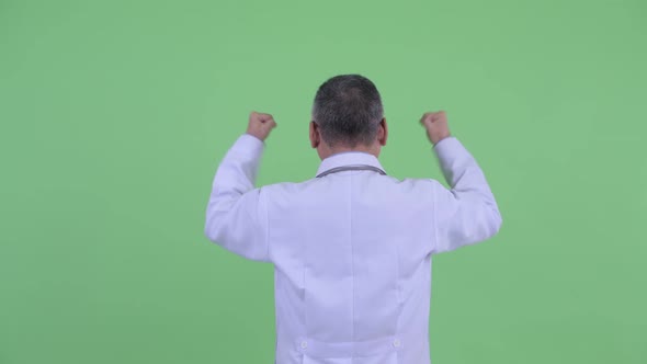 Rear View of Happy Mature Japanese Man Doctor with Fists Raised