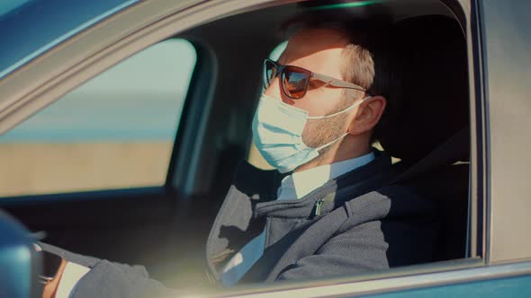 Driver Protective Face Mask In Car. Businessman In Sunglasses Drive Vehicle. Self Isolation On Car.