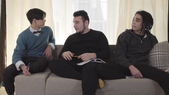 Three Caucasian Male University Students Sitting on Couch and Talking. Adult Friends Chatting