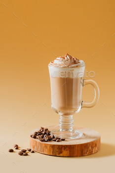 Coffee latte in glass with milk foam on wooden pedestal or stand on yellow / Photodune, Misc