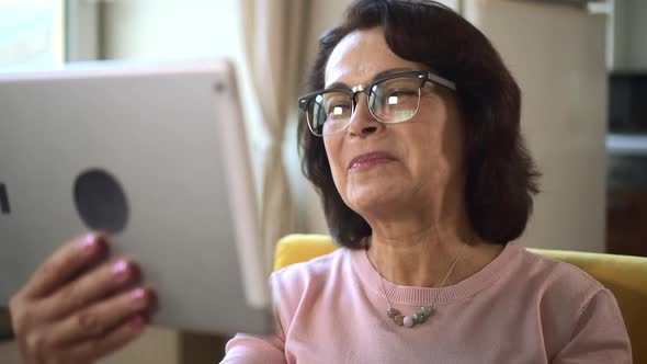 Old Woman Finish Video Call Conversation on Tablet with Waving Hand and Blowing Kiss