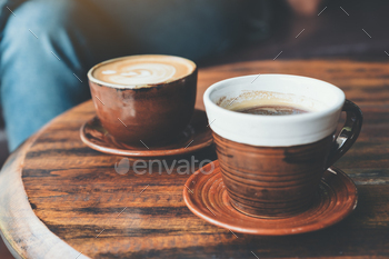 Closeup image of two cups of hot latte coffee and black coffee on vintage wooden table in cafe / Photodune, Misc