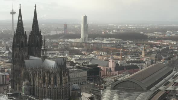 AERIAL: Circling Around Beautiful Cologne Cathedral with Central Train Station in Beautiful Hazy