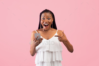 ement, winning lottery or online casino bet on pink studio background. Excited African American woman receiving amazing news on phone