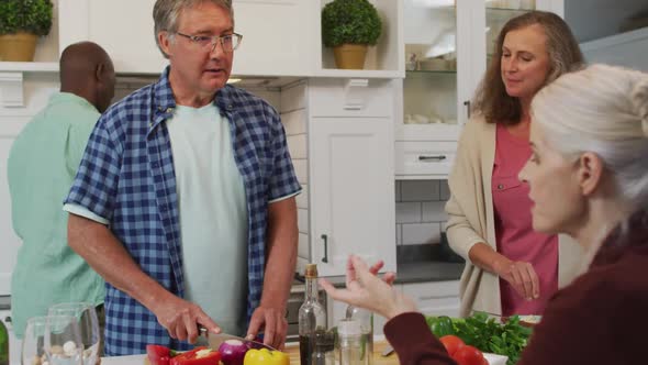 Animation of happy diverse female and male senior friends preparing meal in kitchen, talking