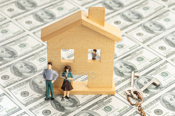 Toy house and figurine couple on dollar banknote background
