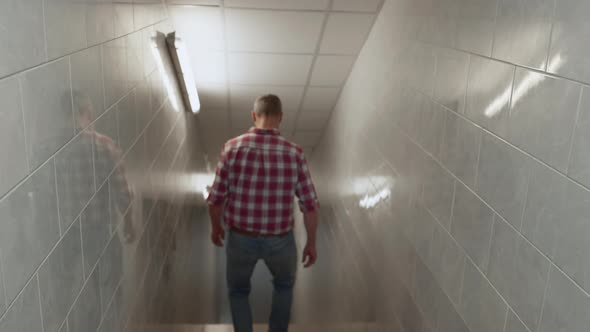 Man Going Downstairs White Corridor Rear View