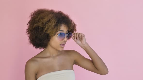 African American Model Poses and Touches Sunglasses on Pink