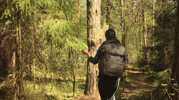 Hiking Woman Walk with a Hiking Backpack in Spring Green Forest