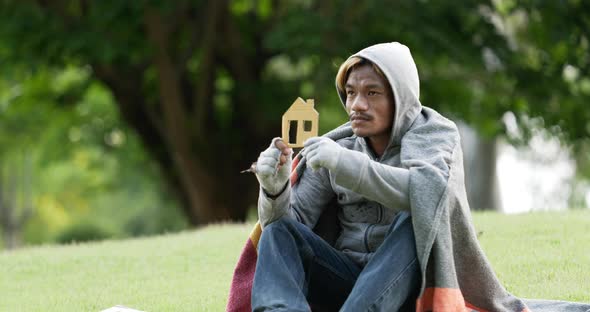 Homeless man sitting and holding home sign