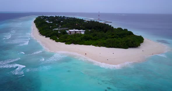Wide angle above island view of a sandy white paradise beach and blue ocean background in vibrant 