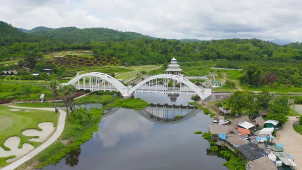 Aerial top view of Tha Chomphu White Bridge, Lamphun, Thailand with lake or river