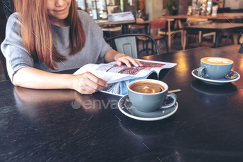 Closeup image of a beautiful asian woman reading magazine with coffee cup on table in modern cafe / Photodune, Misc