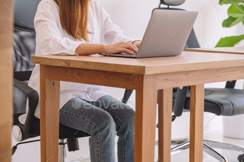 Closeup image of woman using and typing on laptop keyboard on wooden table in office / Photodune, Misc