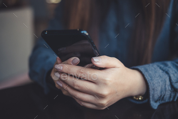 Closeup image of a woman holding , using and looking at smart phone on table / Photodune, Misc
