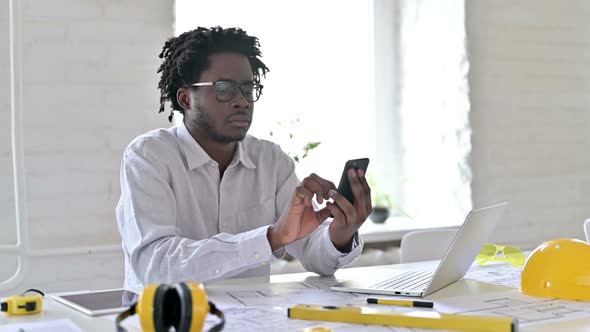 African Engineer Using Laptop and Smartphone