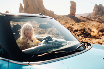 Girl in yellow dress enjoying a road trip in a convertible through a deserted valley with mountains / Photodune, Misc