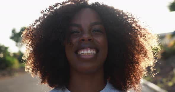 Young african woman smiling in camera with sunset in background
