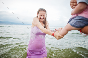 Father, pregnant mother, baby daughter on sea sand beach. / Photodune, Misc