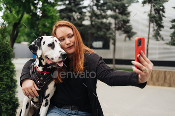 Young woman taking a selfie with mobile phone with her dog in the city. / Photodune, Misc