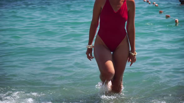 Young Woman with Long Hair in a Red Swimsuit and Bracelets in Boho Style Enjoying the Waves on the