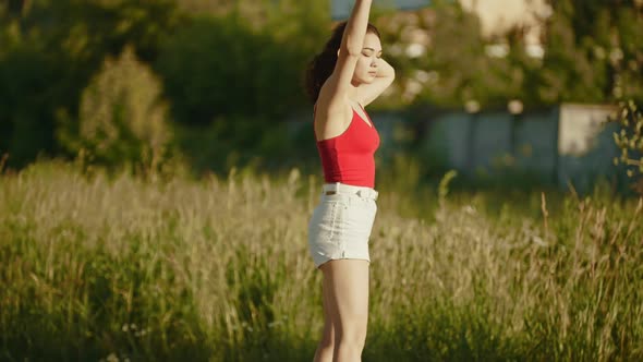 Young Attractive Woman in White Shorts Riding Skateboard on a Background of the High Grass