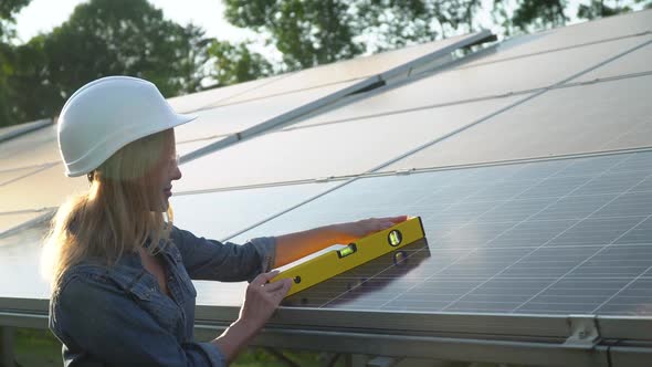 Engineer Female Inspector in a White Helmet Check the Vertical Level of the Solar Panel By Spirit