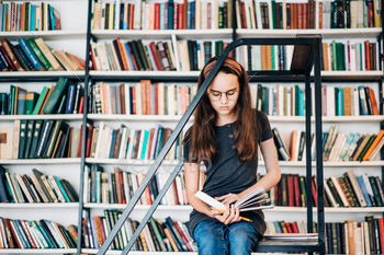 Children's education. Girl reading book at library. / Photodune, Misc