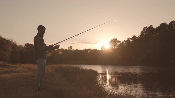 Fisherman with a spinning rod catching fish on a river.