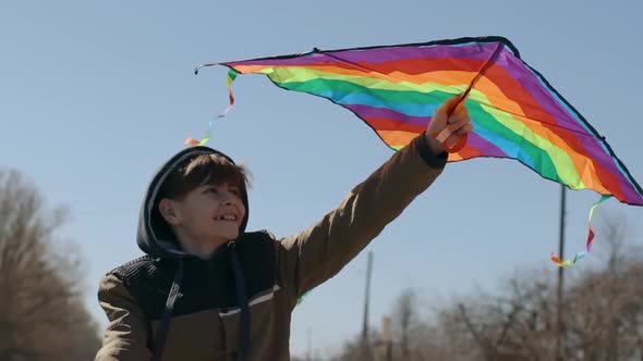 A Happy Boy is Playing with a Flying Rainbow Kite