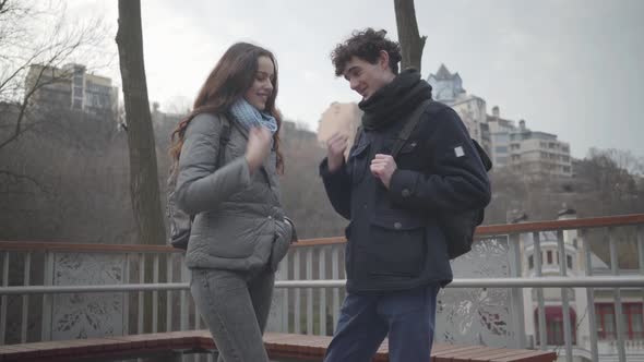 Cheerful Teenage Caucasian Boy Winning at Rock-paper-scissors and Leaving Beautiful Brunette Girl