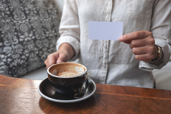 A woman holding and showing a blank empty business card to someone while drinking coffee / Photodune, Misc
