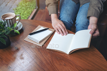 Closeup image of a woman opening a notebooks on wooden table / Photodune, Misc