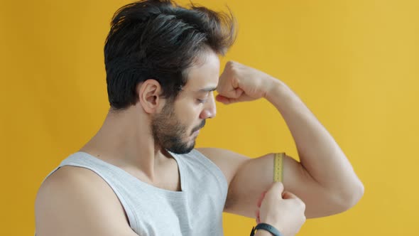 Portrait of Masculine Middle Eastern Guy Bodybuilder Measuring Biceps Muscle with Measure Tape