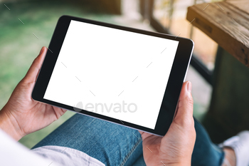 Mockup image of a woman sitting and holding black tablet pc with blank white desktop screen / Photodune, Misc