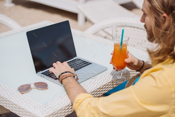 cropped shot of man holding cocktail and using laptop with blank screen outside / Photodune, Misc