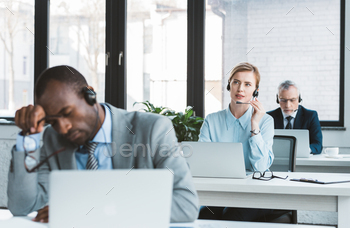 three multiethnic business people in headsets working with laptops in modern office / Photodune, Misc