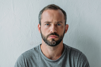 portrait of unhappy bearded man looking at camera on grey / Photodune, Misc