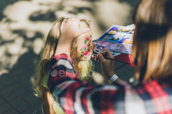 cropped image of woman painting kids face with flowers at street / Photodune, Misc
