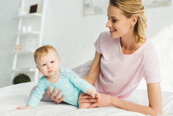 Smiling mother holding baby daughter in bed / Photodune, Misc
