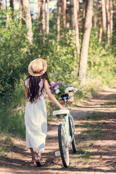 back view of girl in straw hat and white dress walking with bicycle and flowers in wicker basket / Photodune, Misc