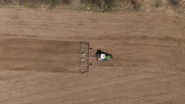 Aerial Top View of Tractor Cutting Furrows in Farm Field for Sowing Farm Tractor with Rotary Harrow