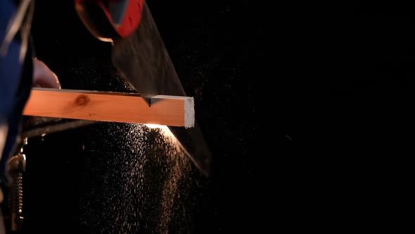 Man Carpenter Saws a Wooden Board with a Hand Saw