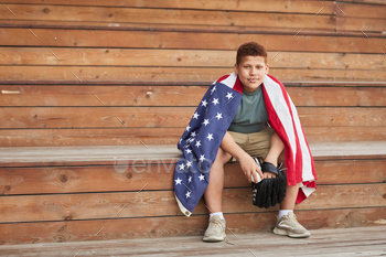 wrapped into American flag sitting on wooden bleacher bench