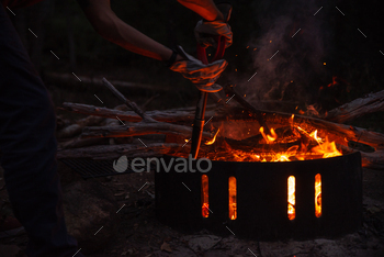 Close Up of Man Hands Tending Fire Pit in a Camping.Outdoor Concept / Photodune, Misc
