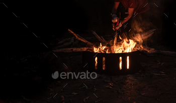 Silhouette of Man Tending a Fire Pit in a Forest at Night Time.Outdoor Concept.Copy Space / Photodune, Misc