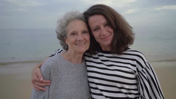 Adult Daughter Hugging Mother and Looking at Camera